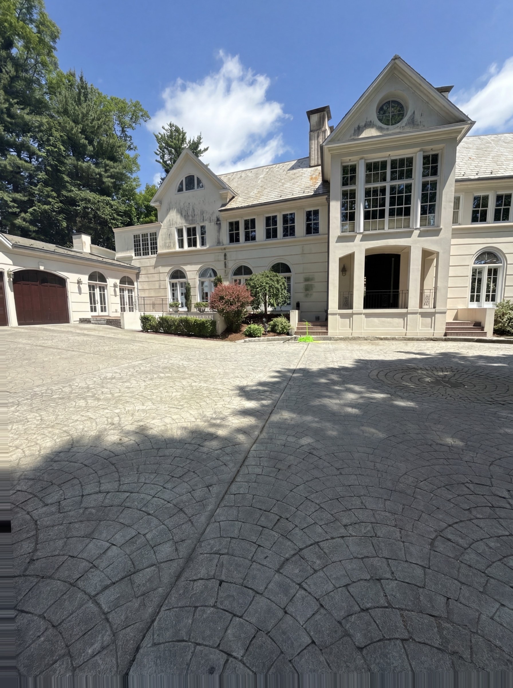 Same stucco facade before pressure washing — visible mildew and atmospheric staining